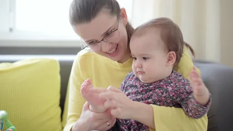 Authentic young caucasian mother keep baby in arms, foot exercises Video stock 149441684