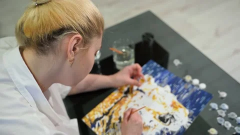 Authentic young woman paints a picture. She is wearing a white shirt. Top view Stock Footage 150489853