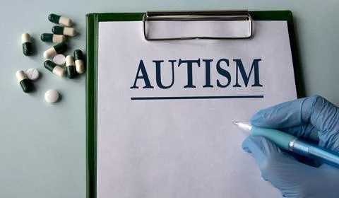 AUTISM - word on a white sheet on the background of a hand in a blue glove .. Stock Photos