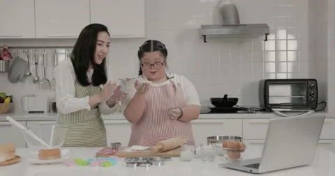 Autistic child practicing cake baking with mother in the kitchen at home Stock Footage 231768188