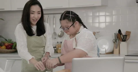 Autistic child practicing cake baking with mother in the kitchen at home Stock Footage 231768564