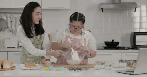 Autistic child practicing cake baking with mother in the kitchen at home Stock Footage 231769457