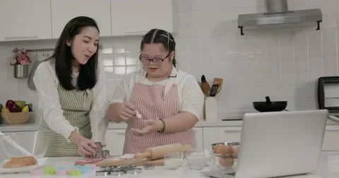 Autistic child practicing cake baking with mother in the kitchen at home Stock Footage 231770206