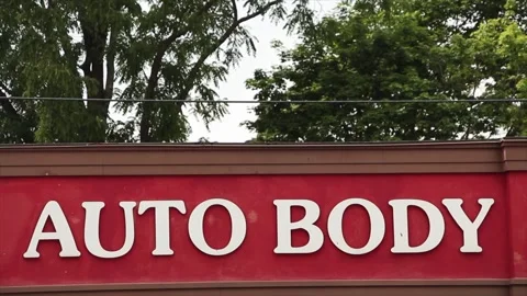 Auto body caption writing text white on red background mechanic shop with trees Stock-Footage 246611299
