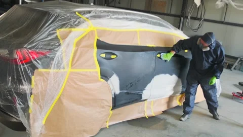 Auto body technician degreasing masked car door surface in repair garage wide Stock Footage 334861551