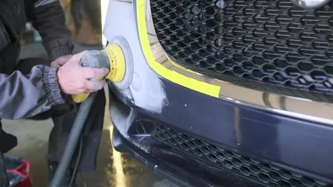 Auto body worker polishing repaired front bumper beside grille with orbital tool Stock Footage 334861779