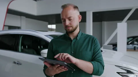 Auto business. Manager with a tablet in his hands, modern dealership Stock Footage 240074823