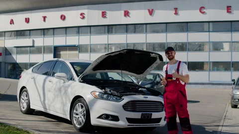 Auto engineer uniform stands by car looks into camera gives thumbs up working Stock Footage 275740835