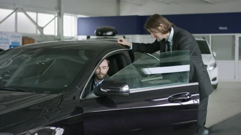 Auto manager is talking to auto buyer sitting in a car. Handsome man is talking Stock Footage 136263476