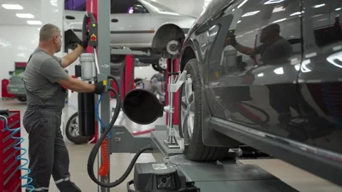 Auto mechanic aligns car wheel with high precision equipment at vehicle service Stock Footage 269030458