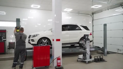 Auto mechanic aligns car wheels using computerized equipment in auto repair shop Stock Footage 261372163