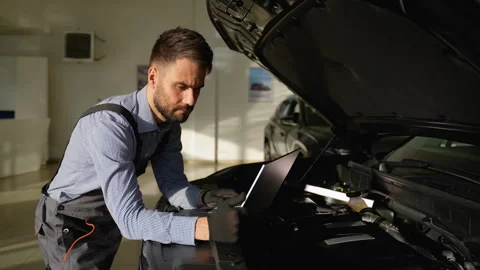 Auto mechanic analyzing car engine diagnostics on laptop Stock Footage 300612549