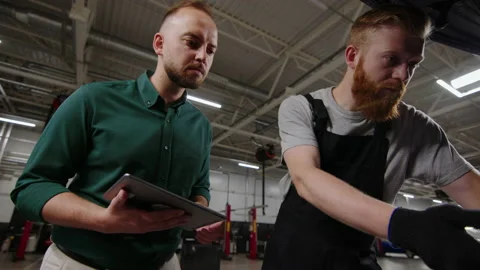 Auto mechanic and a manager inspect the car before repair at a service station Stock Footage 221545475