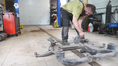 Auto mechanic assembles the subframe of car before installation at garage Stock Footage 254432784