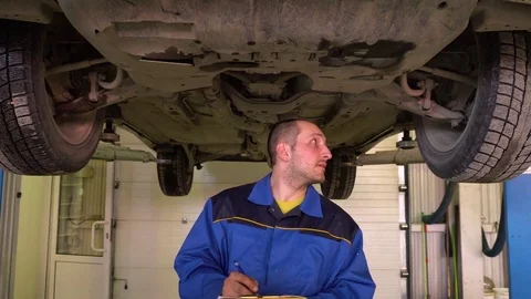 Auto mechanic in blue robe performs diagnostics of the car brake system close-up Stock Footage 75687379
