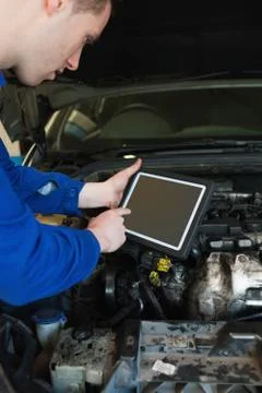 Auto mechanic by car using tablet pc Stock Photos