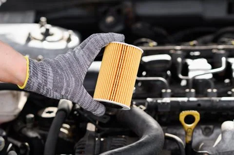 Auto mechanic changes oil filter for diesel cars, holds new oil filter in his Stock Photos