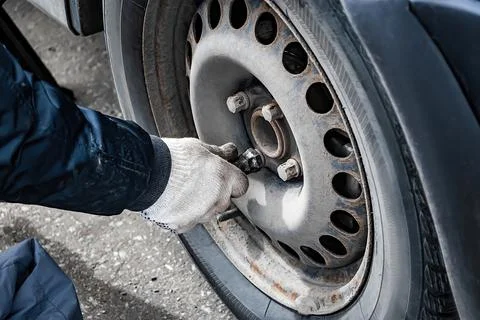 Auto mechanic changes wheel on old car. Stock Photos