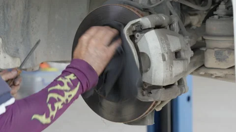 Auto mechanic checking and cleaning a car disc break Stock Footage 239742902