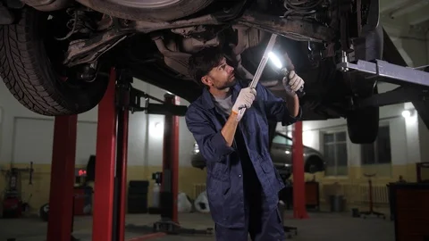 Auto mechanic checking chassis of car on lift Stock Footage 123507592