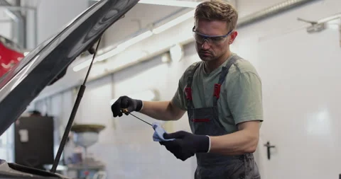 Auto mechanic checking engine oil. Mechanic checking oil level Stock Footage 341867488
