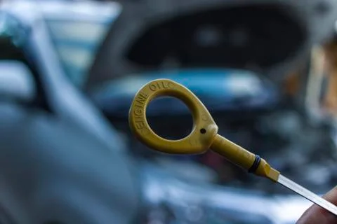 Auto mechanic checking engine oil dipstick in car. Auto mechanic in car repai Stock Photos