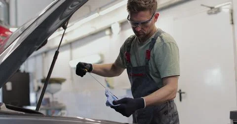 Auto mechanic checking engine oil. Mechanic checking oil level in a car wor.. Stock Photos