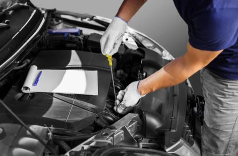 Auto mechanic checking the oil level in car engine Stock Photos
