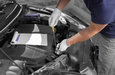 Auto mechanic checking the oil level in car engine Stock Photos