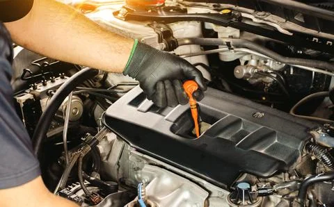 Auto mechanic checking the oil level by dipstick of a car engine. Stock Photos