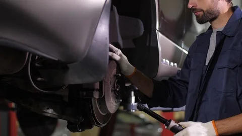 Auto mechanic checking running gear of lifted car Stock Footage 123507240