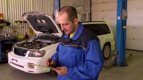 Auto mechanic checks car testing results in garage with tablet in his hands Stock Footage 75686407