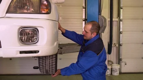 Auto mechanic checks the condition of the car wheel in garage Stock Footage 75687544