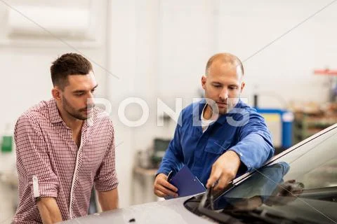 Auto mechanic with clipboard and man at car shop Stock Photos