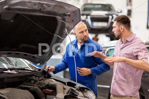 Auto mechanic with clipboard and man at car shop Stock Photos