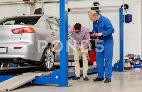 Auto mechanic with clipboard and man at car shop Stock Photos