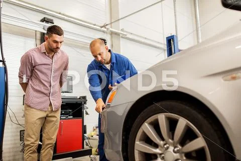 Auto mechanic with clipboard and man at car shop Stock Photos
