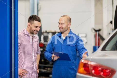 Auto mechanic with clipboard and man at car shop Stock Photos