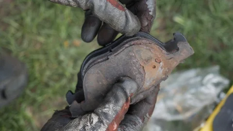 Auto mechanic compares old and new car brake pads Stock Footage 108976432