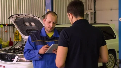Auto mechanic conducts engine diagnostics car using a tablet in garage Stock Footage 75684306
