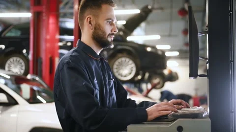 Auto mechanic diagnosing car engine with a laptop with special program Stock Footage 298197504