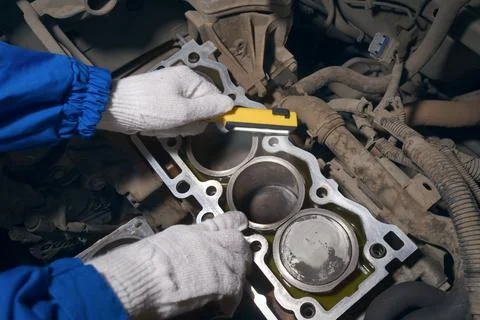 An auto mechanic is diagnosing a car engine with a flashlight. Stock Photos
