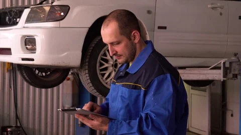 Auto mechanic examines the readings of electronic diagnostics of a car using a Stock Footage 75687886
