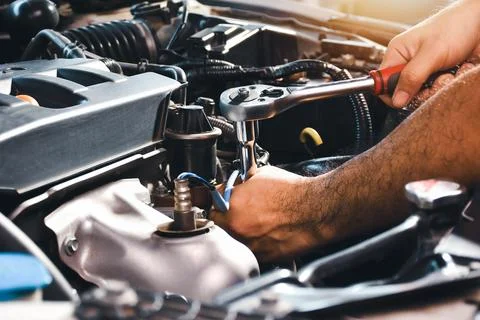 The auto mechanic is fixing the engine of the car with a socket wrench Stock Photos