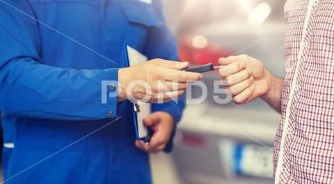 Auto mechanic giving car key to man at workshop Stock Photos