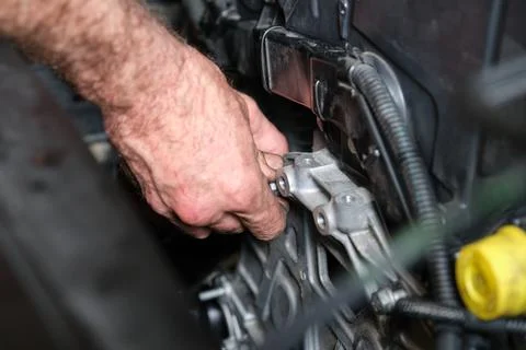 Auto mechanic hands screws the engine mount after replace the timing belt. Foto stock