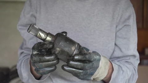 Auto mechanic holding a worn CV joint Stock Footage 332980558