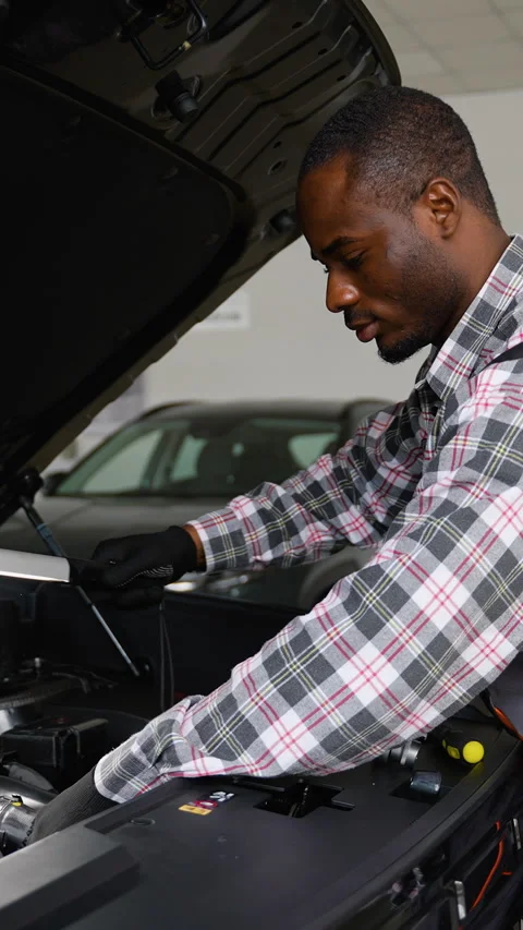 Auto mechanic inspecting car engine with LED work lamp Stock Footage 300614382