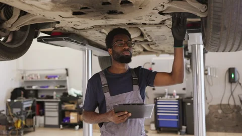 Auto mechanic inspecting car undercarriage with clipboard Video stock 280457901