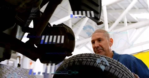 Auto mechanic inspecting hub, lifting and aligning rim onto studs with HUD Stock Footage 334182258